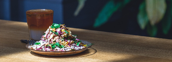 Fresh salad served with an iced beverage on a wooden table in a modern café setting.